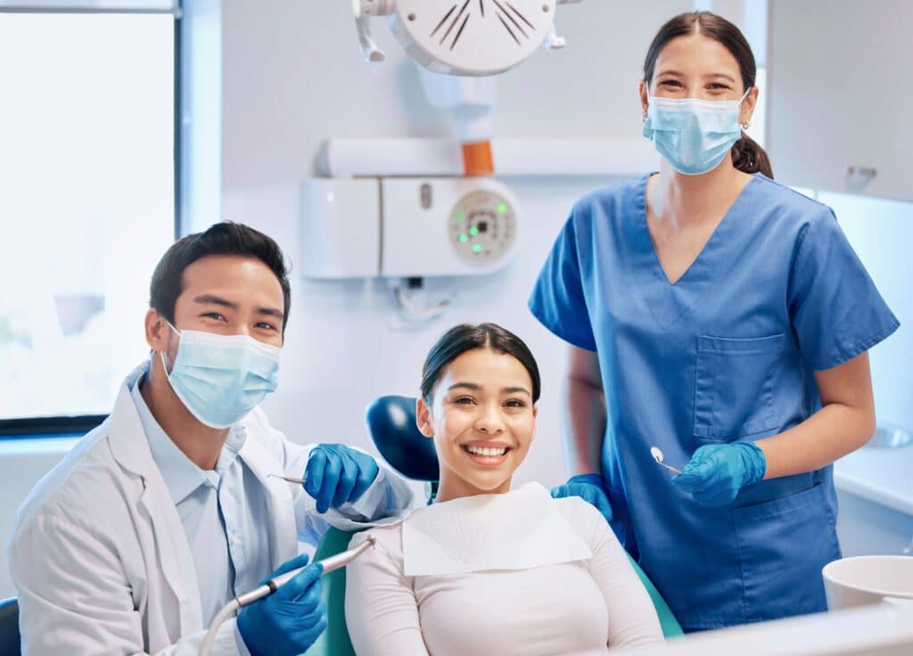 Smiling dental patient with dentist and assistant